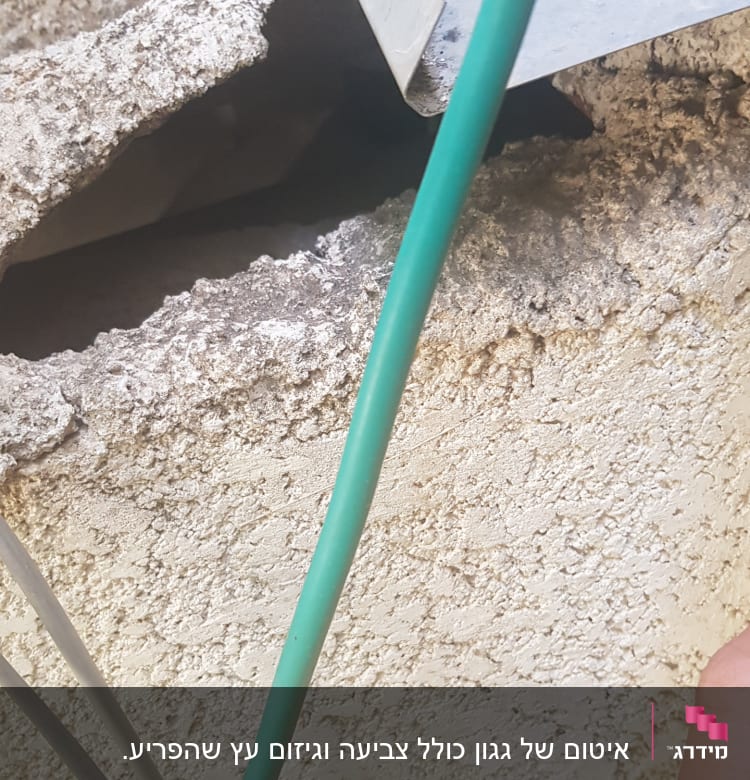 חוט ירוק ליד קיר עם חור וחתיכת מתכת